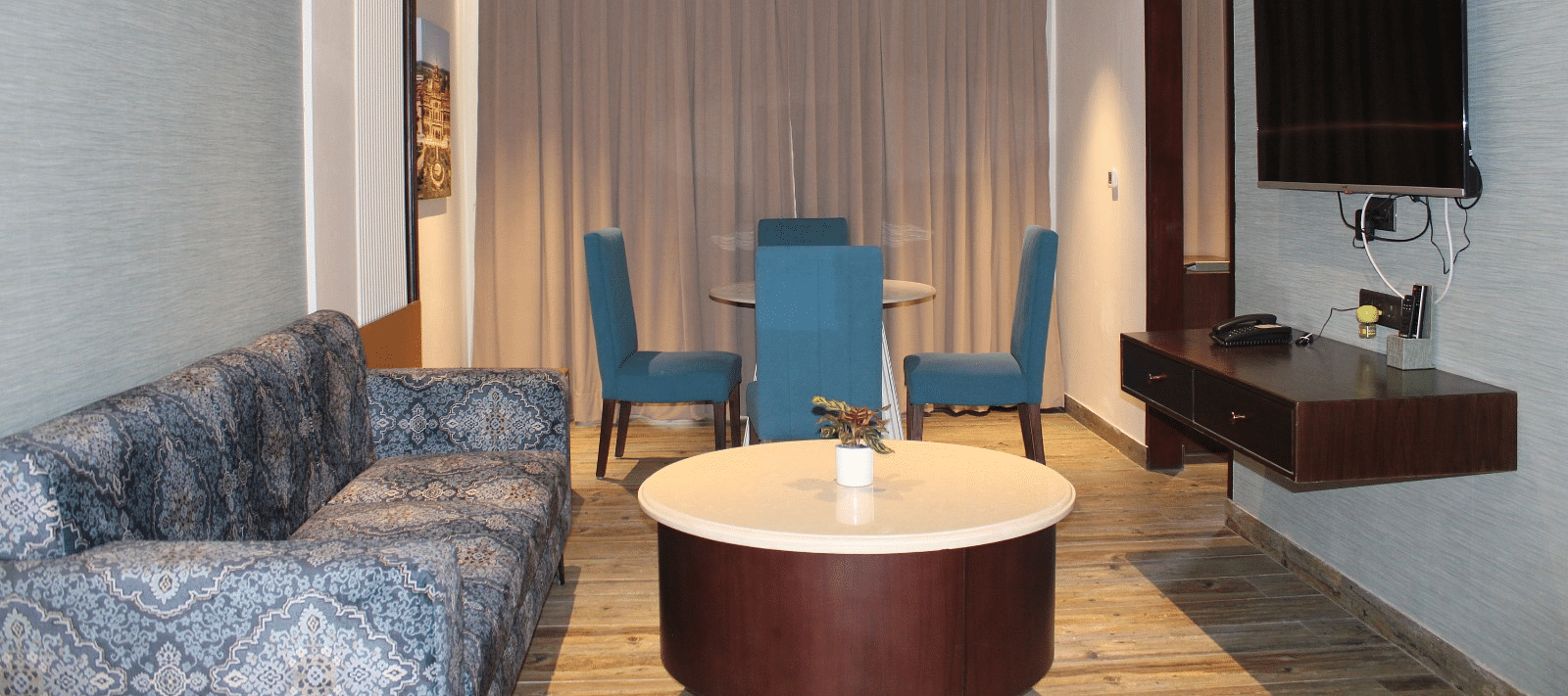 living room of the suite with chairs, a sofa, and a television at BluSalzz Residence, Amritsar